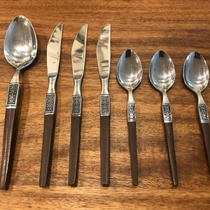 May include: Set of seven silver-toned flatware with brown wooden handles. The handles have a geometric pattern.