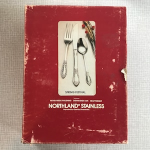 May include: A red box with a silver fork, knife, and spoon on the front. The box says "Spring Festival" and "Northland* Stainless" with the text "Never needs polishing, Dishwasher safe, Heavyweight, Imported by Oneida Silversmiths".