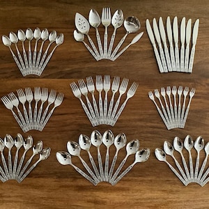May include: A set of silverware with a decorative pattern on the handles. The set includes spoons, forks, and knives.