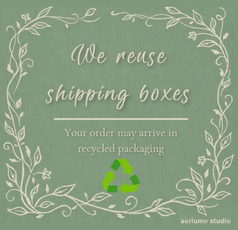 May include: A sage green square sign featuring a white vine border and the text We reuse shipping boxes, Your order may arrive in recycled packaging, and a green recycling symbol. The text aerlume studio is printed in the bottom right corner.