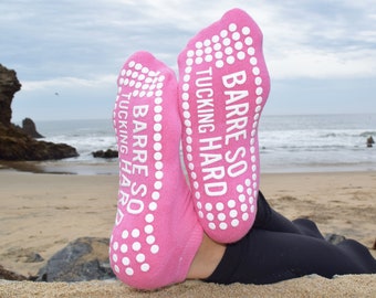 May include: Pink grippy socks with white dots and the text "Barre So Tucking Hard" on the bottom.