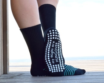 Puede incluir: Calcetines negros antideslizantes con puntos blancos y el texto "my thighs are hungover" en la parte inferior de los calcetines.