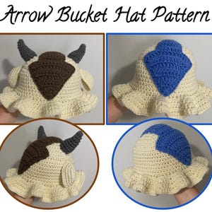 May include: A crochet bucket hat pattern titled Arrow Bucket Hat Pattern. The hat is cream-colored with a ruffled brim and features either a brown or blue arrow design on top. The brown version includes two gray horns and two small side ears.