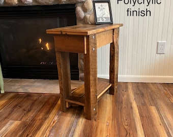 May include: A rustic wooden end table with a shelf, featuring a natural wood finish and a polycrylic top coat. The table is in front of a fireplace with a stone surround.