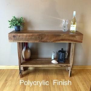 May include: A rustic wooden console table with a single shelf. The table has a natural wood finish and is made of reclaimed wood. The table is 30 inches tall and 48 inches wide. It has a polyacrylic finish.