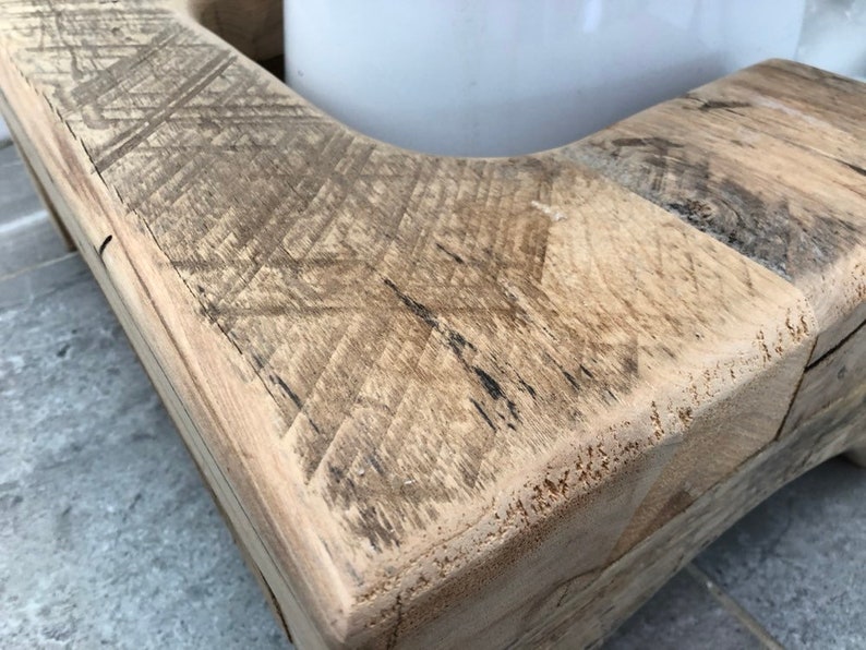 May include: Close-up of a wooden bench with a natural finish. The wood has a distressed look with visible grain and knots. The bench is made of multiple pieces of wood that have been joined together.