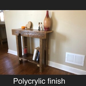 May include: A rustic wooden console table with a shelf, featuring a polycrylic finish. The table is decorated with a vase, a heart-shaped ornament, and two figurines.