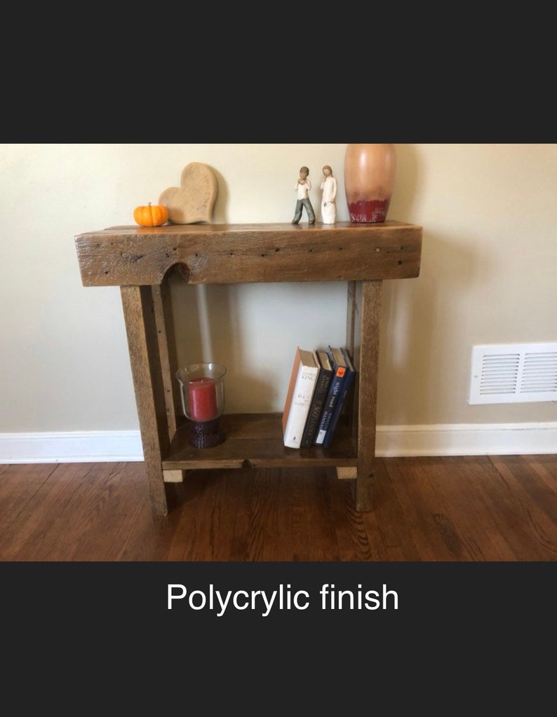 May include: A rustic wooden side table with a shelf, featuring a polycrylic finish. The table has a heart-shaped decorative object, a small orange pumpkin, and two figurines on top. There are books and a candle on the shelf.