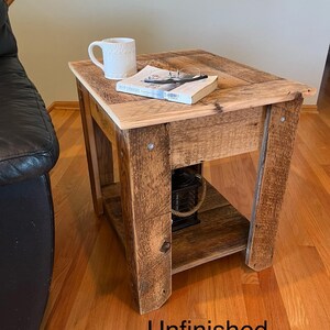 May include: Unfinished wooden end table with a shelf. The table has a rustic, reclaimed wood look and is made of natural wood with knots and grain variations. The table is sitting on a hardwood floor.