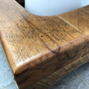 May include: Close-up of a wooden corner of a rustic bench, showing the natural grain and texture of the wood.