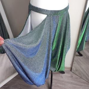 May include: A shimmering green and blue skirt with a slit in the front. The skirt is made of a stretchy, sparkly fabric.
