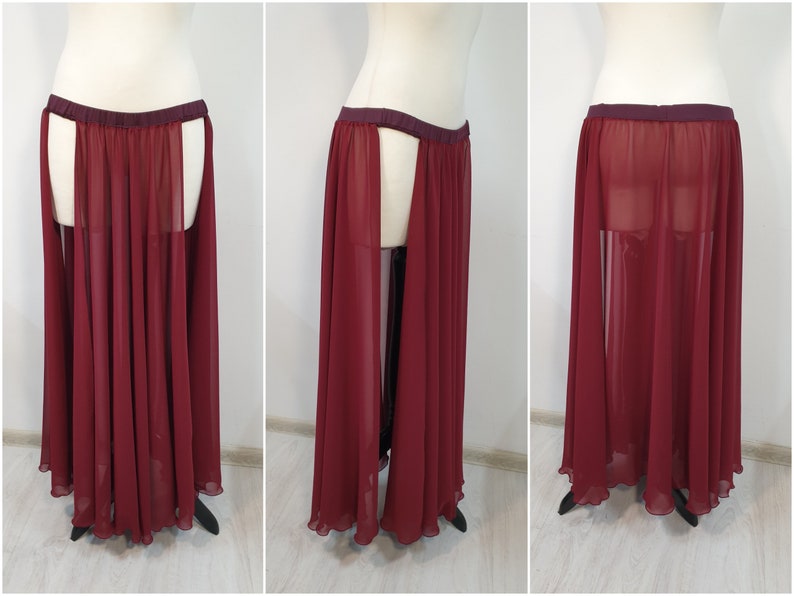 May include: A floor-length, sheer burgundy skirt featuring a dark maroon elastic waistband and high side slits that reveal the legs. The garment is made of a lightweight, flowing chiffon-like fabric that drapes down to the ankles in soft pleats.