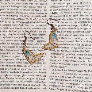 May include: Gold-toned earrings featuring a surrealist melting clock design, reminiscent of Salvador Dalí's artwork. The earrings have a light blue and white face with black hands, and are suspended from a simple hook.