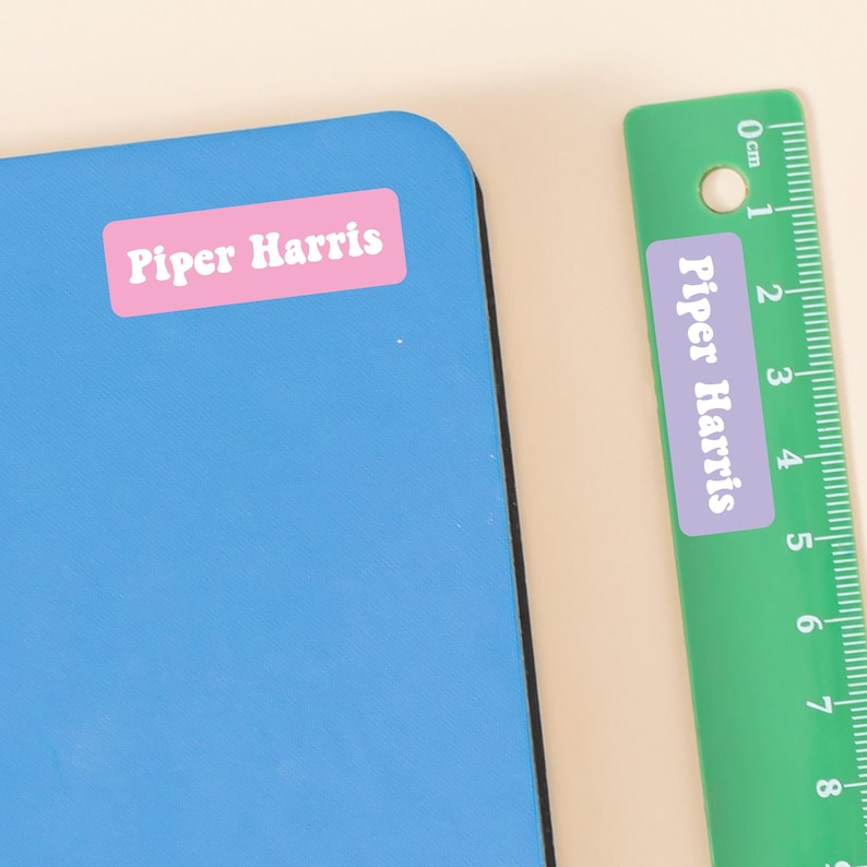 May include: A blue surface with a pink label that reads "Piper Harris." A green ruler with a pink label that reads "Piper Harris" is next to the blue surface. The ruler has centimeter markings.
