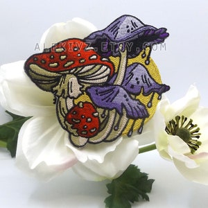 May include: Embroidered patch featuring a cluster of stylized mushrooms in red, purple, and tan, set against a yellow background. The patch has a detailed design with visible stitching and the text "ALEKIVZ.ETSY.COM".