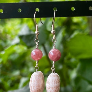 May include: A pair of earrings with pink gemstone beads and white shell charms hanging from silver hooks.