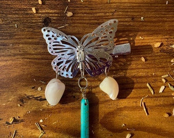 May include: A silver butterfly hair clip with two white shell charms and a turquoise stone pendant.