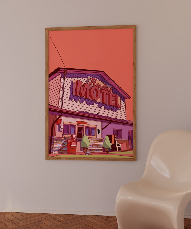 May include: Framed art print featuring a stylized illustration of a motel. The artwork showcases a building with a red and purple neon sign that reads "Rosabel Motel". The color palette includes shades of pink, purple, and brown, with a solid orange background.