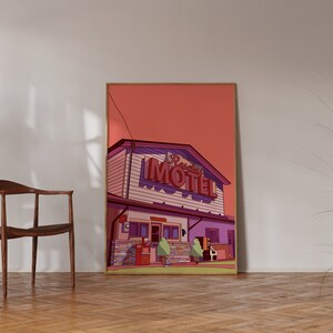 May include: A framed art print featuring a retro illustration of a motel with the name "Reeds" in a neon sign. The artwork has a pink and purple color scheme, with a wooden frame. The print is displayed on a wooden floor.