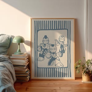 May include: A framed print showcasing three blue robot figures in a stylized design. The artwork is set against a cream background with a blue striped border, within a wooden frame. The print is displayed on a wooden floor.