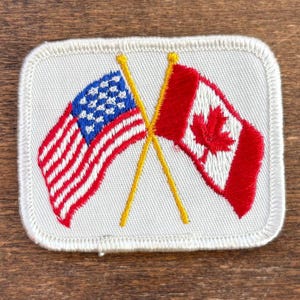 Parche de recuerdo de viaje vintage con las banderas de Estados Unidos (EE. UU.) y Canadá de Voyager