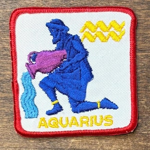 May include: A square embroidered patch with a red border on a white background. It features a blue figure kneeling and pouring water from a purple pitcher. Above the figure are yellow wavy lines, and the word AQUARIUS is stitched in yellow.