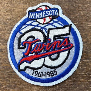 May include: A circular patch featuring the Minnesota Twins logo. The design includes a baseball, the word "MINNESOTA", the number "25", and the word "Twins" in red script. The years "1961-1985" are also displayed.