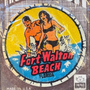 May include: A round, vintage patch featuring a couple in swimwear at the beach. The patch has a yellow background with the words "Fort Walton BEACH FLORIDA" in red and white. The patch is made in the U.S.A.