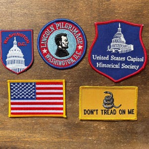 May include: A collection of embroidered patches featuring patriotic and historical themes. Includes a US flag, the Capitol building, and the phrase "Don't Tread on Me." Other patches feature text: "Washington D.C." and "Lincoln Pilgrimage."