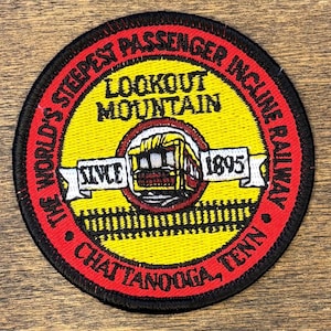 May include: Embroidered patch with a circular design. The patch features a yellow center with the text "LOOKOUT MOUNTAIN" and an illustration of a cable car. The outer ring is red with the text "THE WORLD'S STEEPEST PASSENGER INCLINE RAILWAY CHATTANOOGA, TENN" and "SINCE 1895".