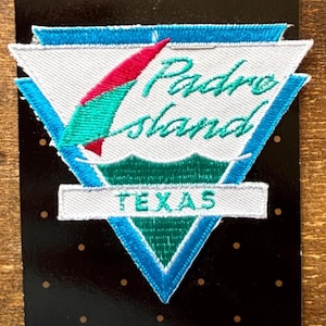 Può includere: Toppa ricamata con la scritta "Padre Island TEXAS". La toppa ha uno sfondo bianco con un bordo blu e turchese. Un disegno rosso e turchese è al centro. Ideale per giacche o borse.