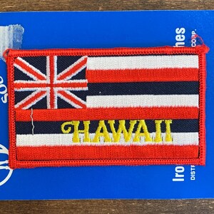 Könnte beinhalten: Ein gestickter Aufnäher mit der Flagge des US-Bundesstaates Hawaii in Rot, Weiß und Blau, mit dem Schriftzug "HAWAII" in gelben Buchstaben.