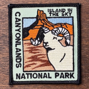 Può includere: Toppa ricamata con un ariete e formazioni rocciose arancioni. La toppa recita "CANYONLANDS NATIONAL PARK" e "ISLAND IN THE SKY" in testo bianco su sfondo verde chiaro. La toppa ha un bordo nero.