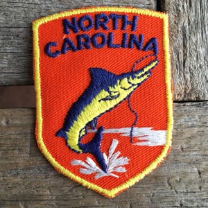 North Carolina Vintage Souvenir Travel Patch from Voyager with orange background