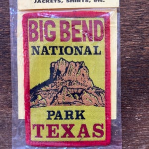 May include: A Big Bend National Park patch with a yellow background and red border. The patch features the words "BIG BEND NATIONAL PARK TEXAS" in red and black lettering, with a mountain graphic.