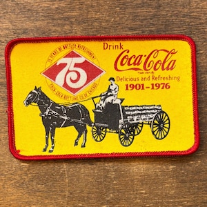 以下が含まれることがあります： 黒いハンドルと「But First, Coffee」のテキストが黒い太字で書かれた白いセラミックマグ。マグは白い表面に置かれています。