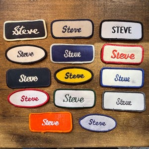 Puede incluir: Una colección de catorce parches bordados rectangulares y ovalados, cada uno con el nombre Steve en varias fuentes, colores de hilo y colores de tela de fondo, incluyendo bordes negros, blancos, azules, rojos, amarillos, naranjas y grises.