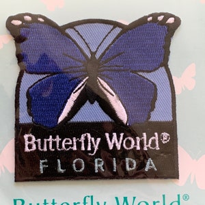 May include: A blue butterfly embroidered patch with the text "Butterfly World® FLORIDA" in white lettering on a black background.