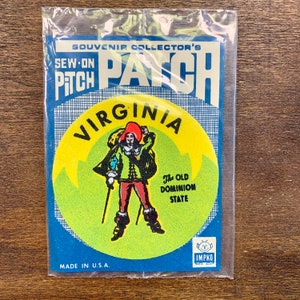 Puede incluir: Un parche de recuerdo de Virginia, empaquetado en plástico transparente. El parche presenta un diseño circular con un fondo amarillo, una figura con atuendo colonial y el texto "VIRGINIA" y "The Old Dominion State". El embalaje dice "SOUVENIR COLLECTOR'S PATCH".