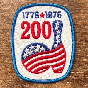 May include: Embroidered patch with a patriotic design. Features the text "1776 1976" and "200" in red, with a bowling pin and ball design incorporating the American flag. The patch has a blue border.