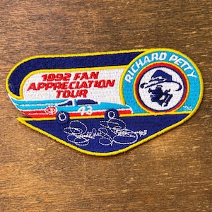 Puede incluir: Parche bordado con un diseño azul, amarillo y blanco. El parche presenta el texto "1992 Fan Appreciation Tour" y un coche de carreras con el número 43. Un emblema circular dice "Richard Petty".