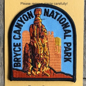 May include: A blue and orange embroidered patch with the text "Bryce Canyon National Park" and a depiction of a tall, thin rock formation.