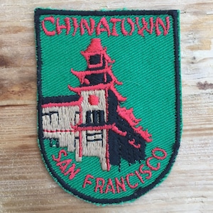 Op de afbeelding: Groen geborduurd patch met een rood en zwart pagodegebouw en de tekst "Chinatown San Francisco".