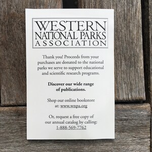 Op de afbeelding: Een witte kaart met zwarte tekst die reclame maakt voor de Western National Parks Association. De kaart legt uit dat de opbrengst van aankopen wordt gedoneerd om educatieve en wetenschappelijke onderzoeksprogramma's te ondersteunen. Het moedigt bezoekers ook aan om hun brede scala aan publicaties te ontdekken, in hun online boekhandel te winkelen of een gratis exemplaar van hun jaarlijkse catalogus aan te vragen door te bellen naar 1-888-569-7762.