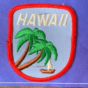 May include: A red, white, and blue embroidered patch with the word "HAWAII" in white lettering and a green palm tree with a brown trunk.