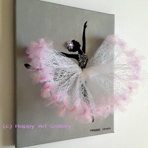 May include: A gray canvas painting with a black silhouette of a ballerina wearing a pink tulle skirt. The skirt is decorated with pink feathers and a purple flower. The painting is signed "Dipsree Samanta" and has the text "(c) Happy Art Gallery" in the bottom left corner.