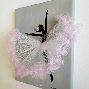 May include: A black silhouette of a ballerina with a pink tulle skirt and a purple flower on her head. The ballerina is painted on a gray canvas.