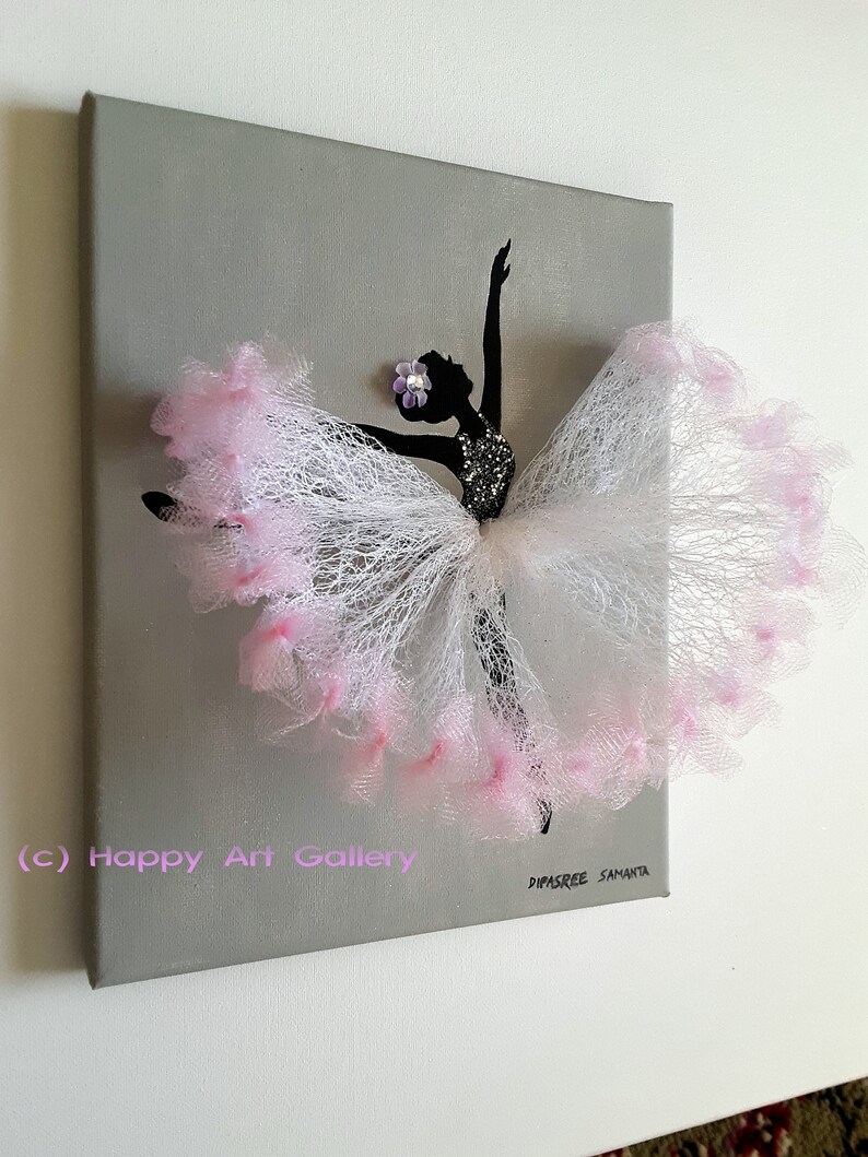 May include: A gray canvas painting with a black silhouette of a ballerina wearing a pink tulle skirt. The skirt is decorated with pink feathers and a purple flower. The painting is signed "Dipsree Samanta" and has the text "(c) Happy Art Gallery" in the bottom left corner.