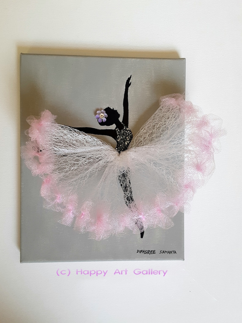May include: A gray canvas painting of a ballerina silhouette with a pink tulle skirt. The ballerina is wearing a flower on her head and the painting is signed "Dipasree Samanta" and "(c) Happy Art Gallery".