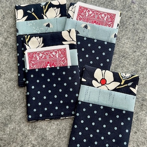 May include: Three rectangular fabric card holders featuring a layered design. The top section has a dark navy background with white floral patterns, the middle is light blue with small umbrella icons, and the bottom is navy with white polka dots.